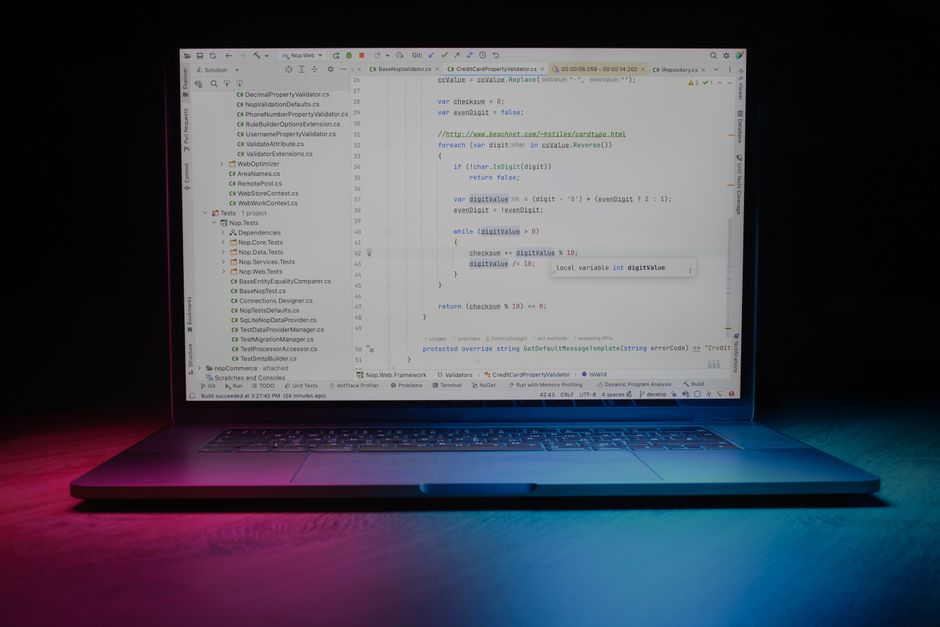 Persona escribiendo sus primeras líneas de código en un cuaderno junto a una laptop